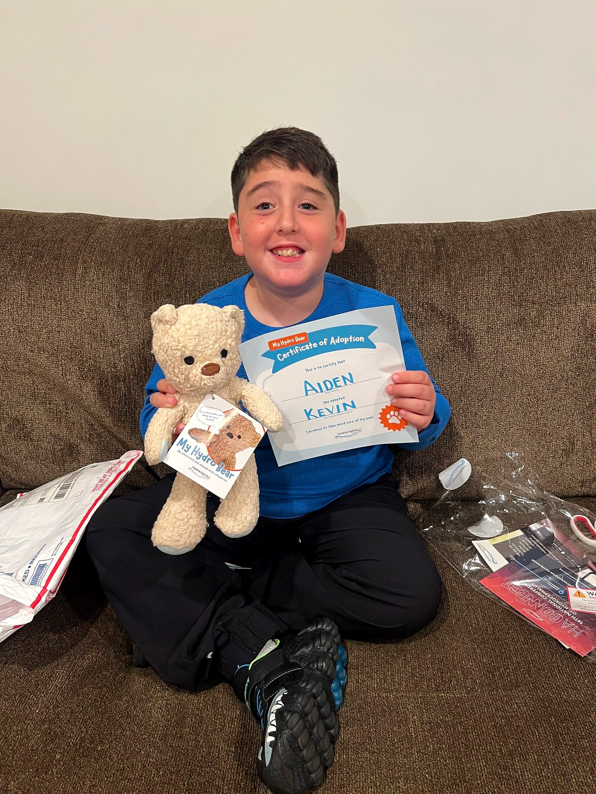 A smiling boy holding his Hydro Bear and a certificate