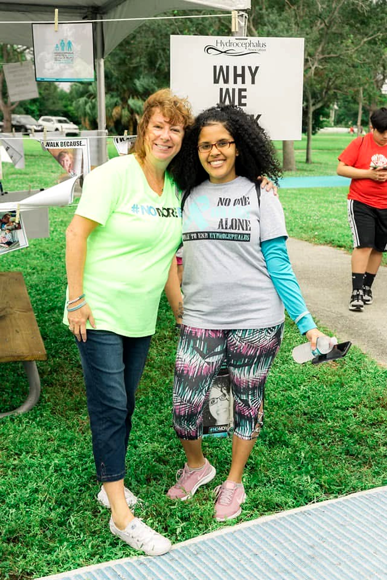 Two WALK participants smiling in front of a Why We Walk sign